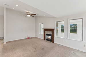 Unfurnished living room featuring lofted ceiling, light carpet, ceiling fan, a tile fireplace, and recessed lighting