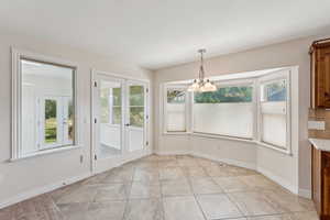 Unfurnished dining area with a chandelier, french doors, and light tile patterned flooring