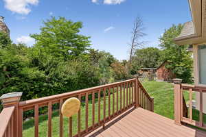 Wooden deck featuring a lawn and a storage shed