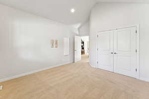 Unfurnished bedroom featuring light colored carpet, high vaulted ceiling, a closet, and recessed lighting