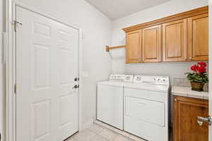 Laundry room featuring cabinet space, washing machine and dryer, and light tile patterned floors