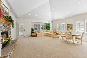 Carpeted living area with a fireplace, high vaulted ceiling, and recessed lighting