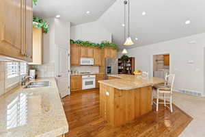 Kitchen featuring white appliances, washer and clothes dryer, a kitchen island, a breakfast bar, and backsplash
