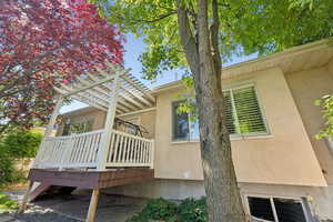 View of property exterior featuring stucco siding, a deck, and a pergola