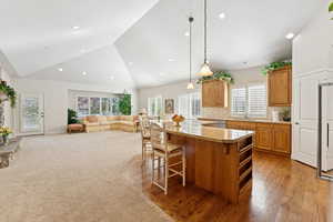 Kitchen with stainless steel dishwasher, a center island, a breakfast bar, hanging light fixtures, and recessed lighting