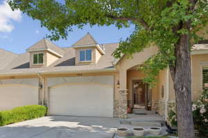 Multi unit property featuring stone siding, stucco siding, driveway, an attached garage, and a shingled roof