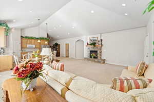 Living room with high vaulted ceiling, light colored carpet, recessed lighting, and a fireplace