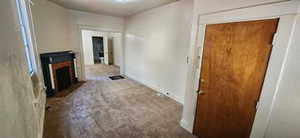 Unfurnished living room featuring carpet floors and a fireplace