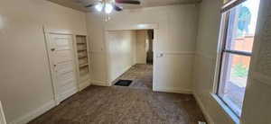 Carpeted empty room featuring plenty of natural light and ceiling fan