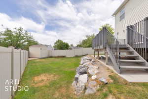 Fenced backyard featuring stairs, a wooden deck, and a storage shed