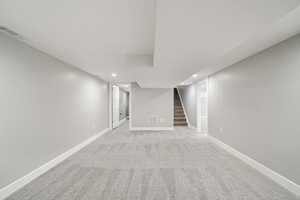 Finished below grade area with recessed lighting, stairs, and carpet