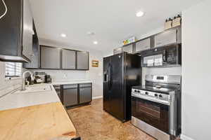 Kitchen with black appliances, light countertops, recessed lighting, and light flooring