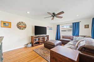Living area featuring light wood-style flooring, a ceiling fan, and recessed lighting