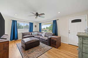 Living room with ceiling fan, light wood-style floors, and recessed lighting