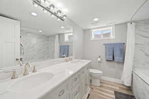 Full bath featuring double vanity, recessed lighting, shower / tub combo with curtain, and wood finished floors