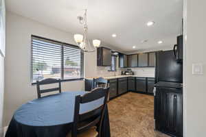 Kitchen with black appliances, light countertops, recessed lighting, hanging light fixtures, and a chandelier