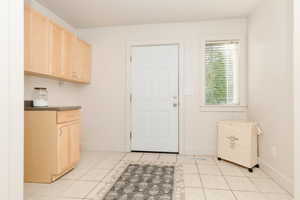 Laundry room with light tile patterned flooring and baseboards