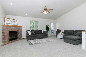 Carpeted living area with a ceiling fan, lofted ceiling, a fireplace, and recessed lighting