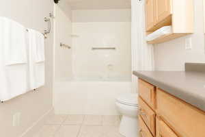 Full bath with tile patterned floors, vanity, and shower / bath combo