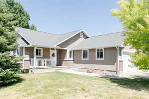 View of front of home featuring stucco siding, covered porch, a garage, and a front yard