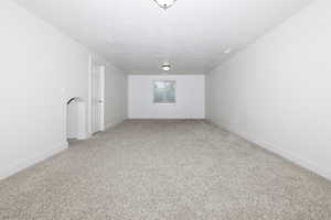 Unfurnished room featuring light carpet and baseboards
