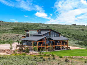 Back of house featuring a lawn, a wooden deck, and a shingled roof
