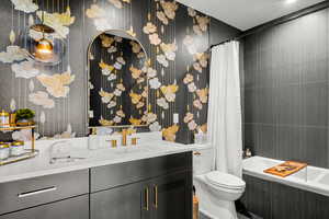Full bath featuring vanity, wallpapered walls, and tiled shower / bath