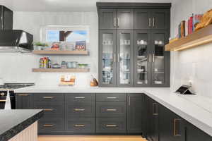 Kitchen area featuring gas stove, tasteful backsplash, and wall chimney range hood