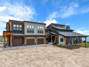 View of front facade with dirt driveway, board and batten siding, a garage, and stone siding