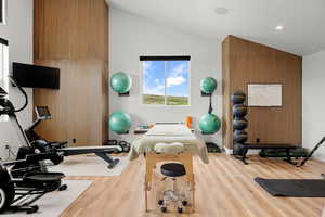 Exercise room with wood finished floors, lofted ceiling, and recessed lighting