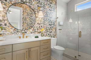 Full bath featuring wallpapered walls, vanity, a shower stall, and a ceiling fan