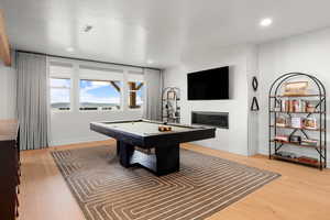 Recreation room with light wood-type flooring, pool table, a tile fireplace, and recessed lighting