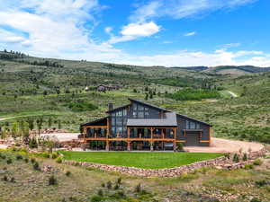 Back of house featuring driveway, a lawn, a deck, and a chimney