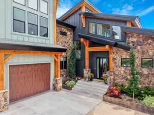 Modern home with stone siding, board and batten siding, an attached garage, and concrete driveway
