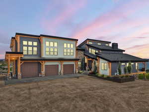 View of front of property featuring board and batten siding, a garage, driveway, and stone siding