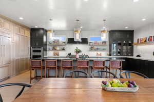 Kitchen with open shelves, light countertops, a kitchen bar, dark cabinetry, and recessed lighting