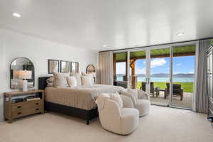 Carpeted bedroom featuring a water and mountain view, access to exterior, multiple windows, and recessed lighting