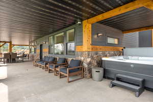 View of patio with an indoor hot tub, outdoor lounge area, and outdoor dining space