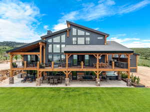 Back of property featuring a patio area, a lawn, a shingled roof, and a deck