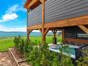 View of patio / terrace with a hot tub and a water and mountain view