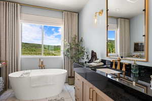 Master Bathroom featuring marble look tiles, a freestanding bath, and vanity