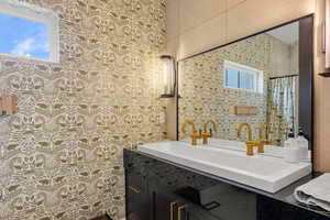 Bathroom featuring wallpapered walls, healthy amount of natural light, and vanity