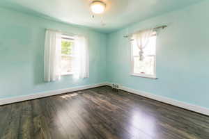 Empty room with dark wood-style flooring and baseboards