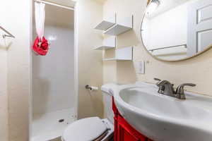 Full bathroom featuring a stall shower, a textured wall, and vanity