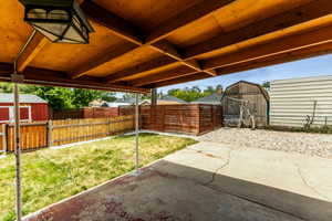 Fenced backyard featuring a storage shed and a patio