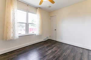 Empty room featuring dark wood-style floors, a ceiling fan, and a smoke detector