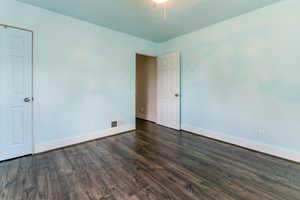Spare room featuring baseboards and dark wood finished floors