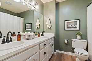 Bathroom featuring double vanity and wood finished floors