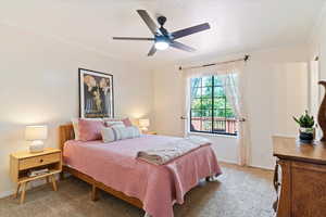 Bedroom with light colored carpet, crown molding, and a ceiling fan