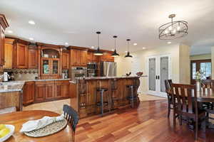 Kitchen featuring stainless steel appliances, brown cabinets, a center island, decorative backsplash, and recessed lighting
